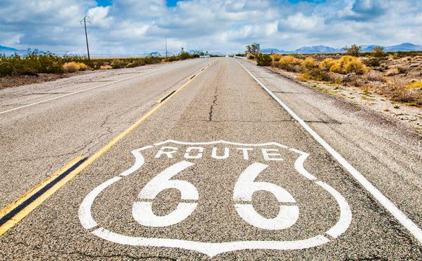 Route 66 road sign with blue sky background. Historic street with nobody. Classic concept for travel and adventure in a vintage way. - Photo, Image
