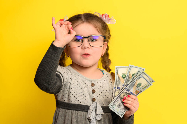 Ei-lapsi säästää rahaa lasten käsissä, keltainen tausta ja rahaa vauvan kanssa. uusi - Valokuva, kuva