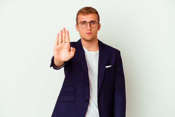 Jonge zakelijke blanke man geïsoleerd op witte achtergrond staan met uitgestrekte hand tonen stopteken, voorkomen dat u. - Foto, afbeelding
