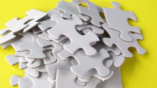 Rotazione di puzzle bianco puzzle in bianco su superficie gialla - Filmati, video