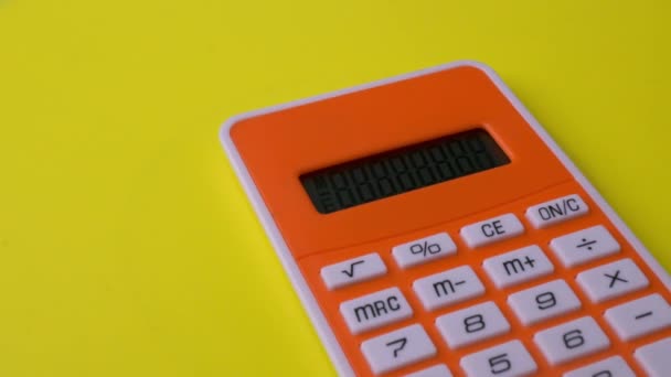 Primer plano plano de la calculadora rotar sobre la superficie amarilla - Imágenes, Vídeo