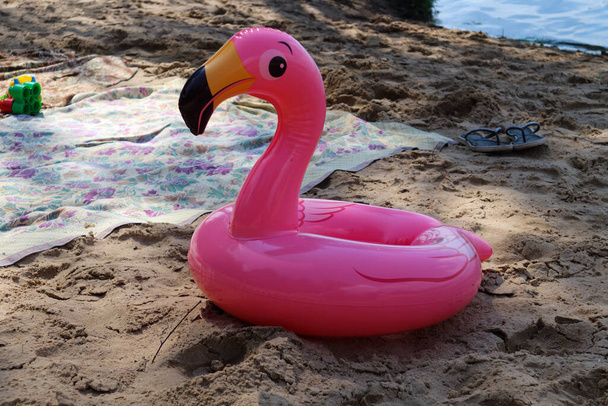 Sahilde çocukların can simidi. Parlak çocukların şişme dairesi sahilde yerde yatıyor. Pembe Flamingo şeklindeki can simidi - Fotoğraf, Görsel