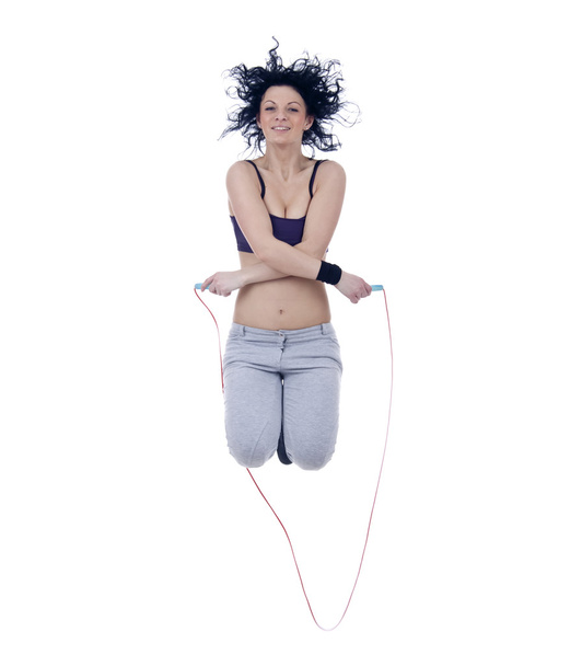 Жінка стоїть в спортивному одязі стрибає з пропускаючою мотузкою
 - Фото, зображення
