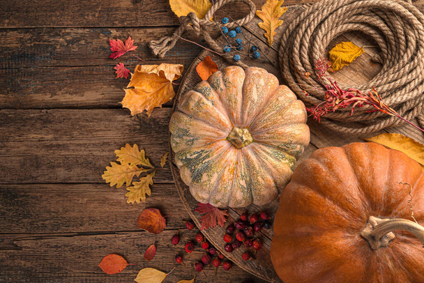 Tökfélék és sárga levelek, fa barna háttérrel. Háttér őszi ünnepek: Hálaadás, Halloween. Felülnézet. - Fotó, kép