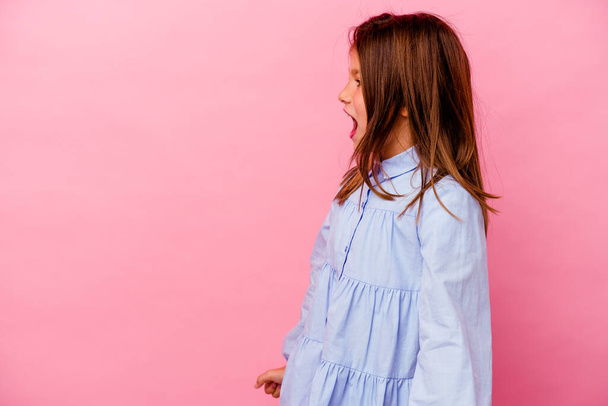 Pequena menina caucasiana isolado em fundo rosa gritando em direção a um espaço de cópia - Foto, Imagem