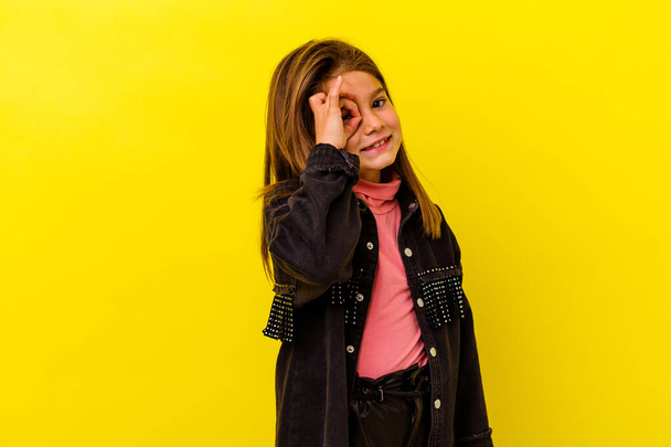 Little caucasian girl isolated on yellow background excited keeping ok gesture on eye. - Foto, Imagem
