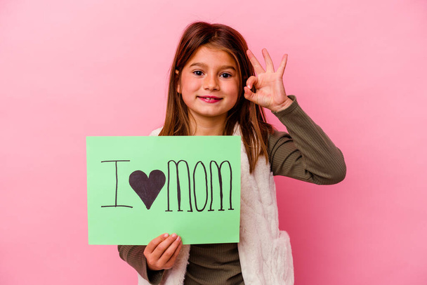 Little girl holding an I love mum placard isolated on pink background - Foto, Bild