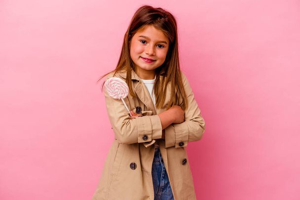Kis kaukázusi lány kezében egy nyalóka elszigetelt rózsaszín háttér nevetés és szórakozás. - Fotó, kép