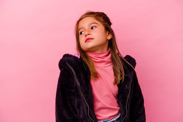 Μικρή καυκάσια κοπέλα απομονωμένη σε ροζ φόντο ονειρεύεται την επίτευξη στόχων και σκοπών - Φωτογραφία, εικόνα