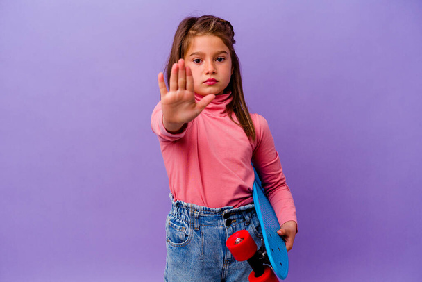 Piccolo pattinatore caucasico ragazza isolata su sfondo blu in piedi con mano tesa mostrando segno di stop, impedendo voi. - Foto, immagini