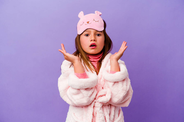 Malá kavkazská dívka nosí pyžamo izolované na fialovém pozadí překvapené a šokované. - Fotografie, Obrázek