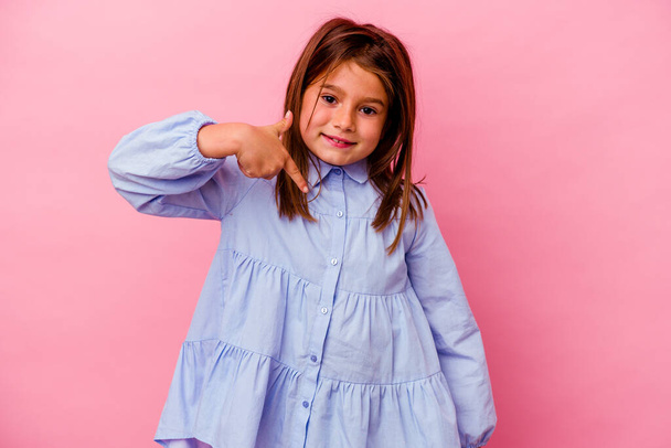 Маленька біла дівчинка ізольована на рожевому фоні, вказуючи вручну на простір для копіювання сорочки, горда і впевнена
 - Фото, зображення