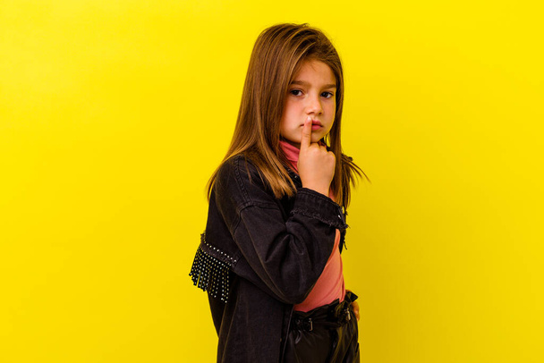 Little caucasian girl isolated on yellow background unhappy looking in camera with sarcastic expression. - Foto, imagen