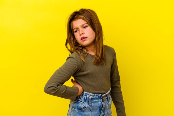 Little caucasian girl isolated on yellow background suffering a back pain. - Foto, Imagem