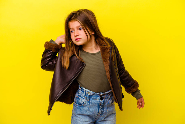 Little caucasian girl isolated on yellow background trying to listening a gossip. - Fotografie, Obrázek