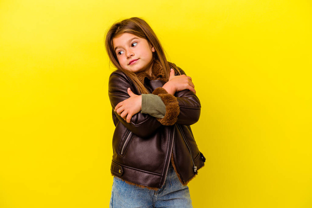 Little caucasian girl isolated on yellow background hugs, smiling carefree and happy. - 写真・画像