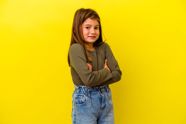 Маленькая кавказская девочка на желтом фоне смеется и веселится. - Фото, изображение