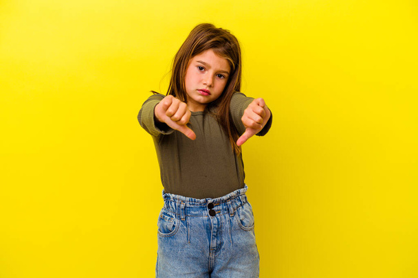 Little caucasian girl isolated on yellow background showing thumb down and expressing dislike. - 写真・画像