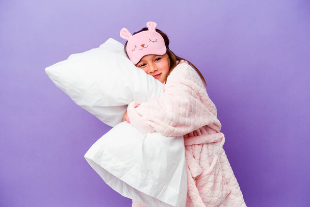 Kleines Mädchen umarmt ein Kissen glücklich isoliert auf lila Hintergrund - Foto, Bild