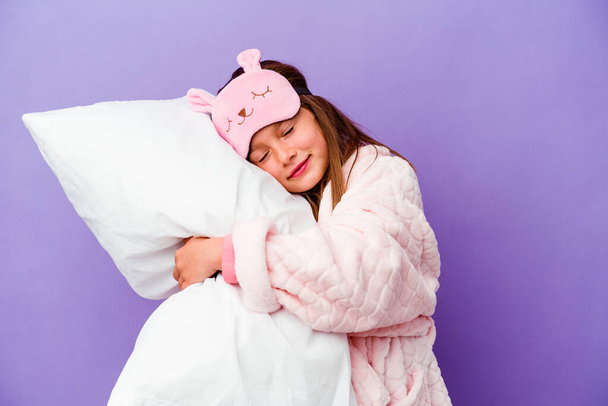 Kleines Mädchen umarmt ein Kissen glücklich isoliert auf lila Hintergrund - Foto, Bild