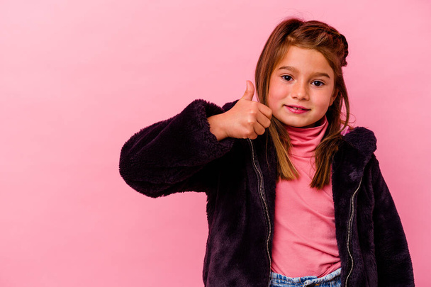 Kis kaukázusi lány elszigetelt rózsaszín háttér mosolyog és felemeli hüvelykujját - Fotó, kép