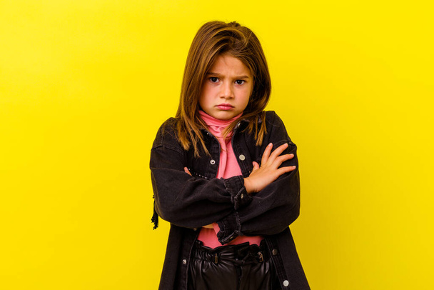 Little caucasian girl isolated on yellow background blows cheeks, has tired expression. Facial expression concept. - Photo, Image