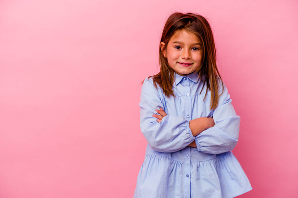 Pequena menina caucasiana isolado no fundo rosa sorrindo confiante com braços cruzados. - Foto, Imagem