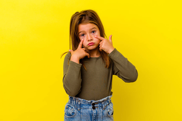 Little caucasian girl isolated on yellow background crying, unhappy with something, agony and confusion concept. - Фото, изображение