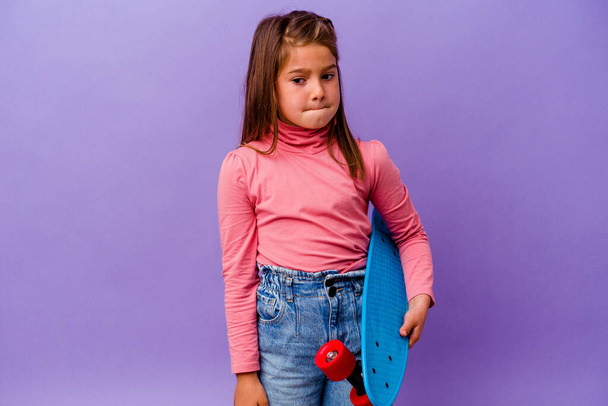 Piccolo pattinatore caucasico ragazza isolata su sfondo blu confuso, si sente dubbioso e insicuro. - Foto, immagini