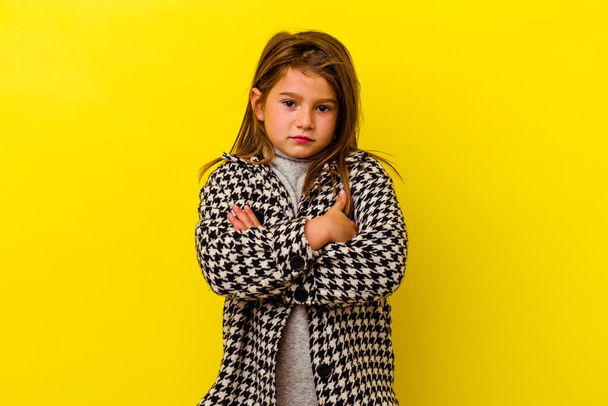 Little caucasian girl isolated on yellow background frowning face in displeasure, keeps arms folded. - Foto, afbeelding