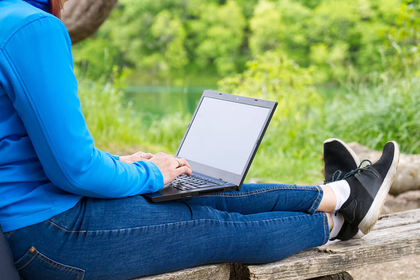 Young woman, female freelancer working with laptop with Beautiful view of forest and lake. - Foto, afbeelding