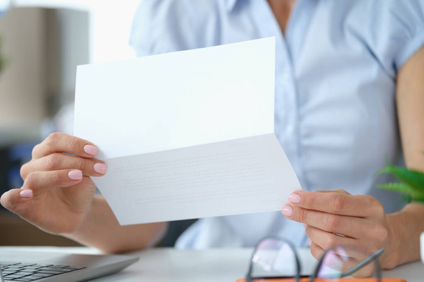 Woman reading letter while sitting at table with open envelope - Photo, Image
