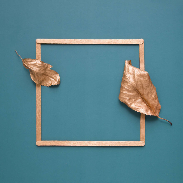 Плоская укладка золотых листьев и рамка на бирюзовом фоне с копировальным пространством. Минималистическая концепция уборки, осень - Фото, изображение