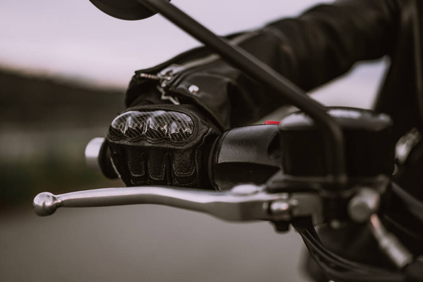Hand of driver in road gloves who twists accelerometer lever while standing. Biker culture, cafe racers, motorbike aesthetics and vintage design concept. concept. - Foto, afbeelding