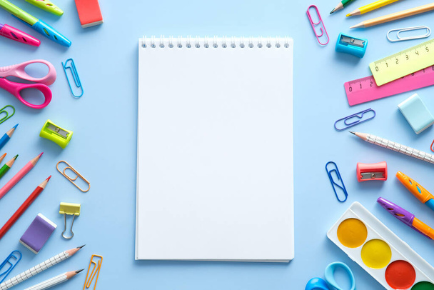 School supplies and notepad on blue background. Back to school concept. Flat lay, top view, overhead. - Foto, Imagem