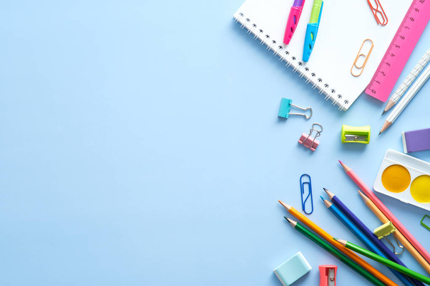 School stationery, color pencils, paints, notepad on blue table. Back to school background. Kids desk top view. - Zdjęcie, obraz