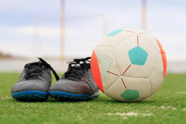 voetbalschoenen en de bal op het gras - Foto, afbeelding