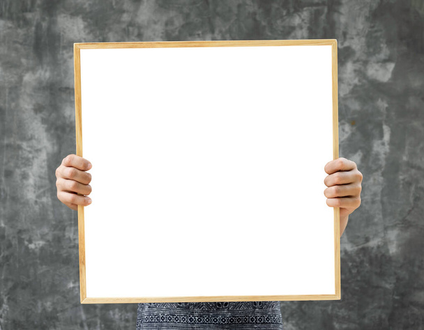 Mockup white blank space in a square wooden frame. Artist's hands showing blank square space in a wood frame on grunge grey cement wall background. - Photo, image