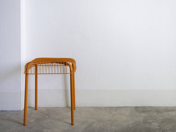 Пустой DIY стул оранжевого цвета из стали и проволоки на бетонном полу и белом фоне стены с копировальным пространством. Современное кресло с геометрической сеткой. - Фото, изображение