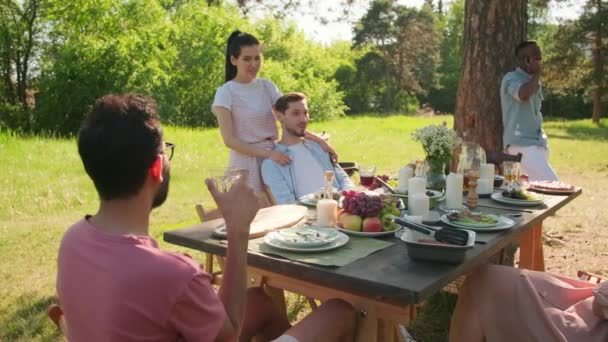 Eine Gruppe junger Freunde verbringt das Wochenende zusammen in einem wunderschönen Park im Freien und entspannen sich, essen zu Mittag und plaudern - Filmmaterial, Video