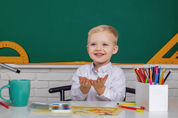 Kids gets ready for school. Friendly child in classroom near blackboard desk. Individual teaching. - Foto, Imagem