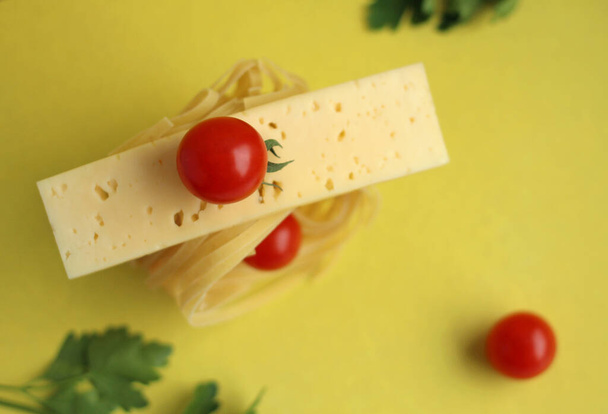Pasta muodossa pesä tomaatit ja persilja keltaisella pohjalla. Tuotetase - Valokuva, kuva