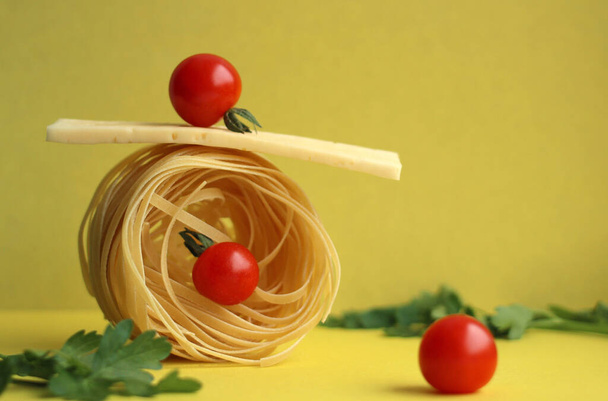 Pasta in the form of a nest with tomatoes and parsley on a yellow background. Product Balance - Photo, Image
