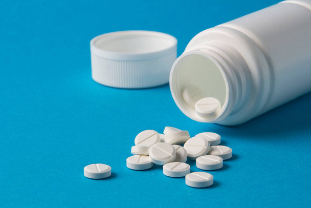 witte pot voor pillen en vitaminen op een blauwe achtergrond - Foto, afbeelding