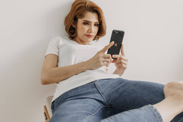 Woman resting and relax in the room with her smartphone in hand. - Photo, Image