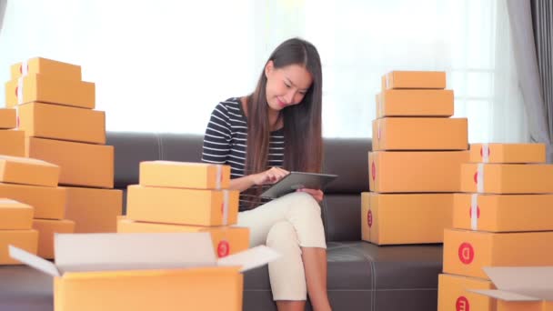 filmato di bella donna asiatica che lavora a casa con pacchi in scatole - Filmati, video