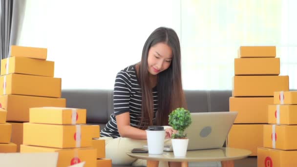 кадры красивой азиатской женщины, работающей дома с посылками в коробках - Кадры, видео
