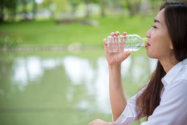 Jeune femme Boire de l'eau de la bouteille dans le jardin vert Park. Asiatique femme bouteille d'eau potable personne en bonne santé heureux et souriant. Bonheur Belles femmes asiatiques chinoises tenant bouteille d'eau minérale - Photo, image