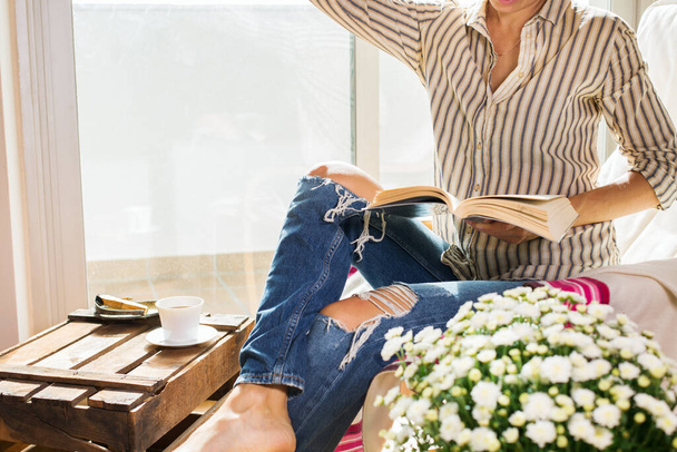 Junge Frau entspannt sich zu Hause, trinkt Tee, liest Buch - Foto, Bild