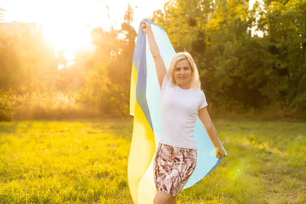 beautiful woman holding a flag of Ukraine - Foto, afbeelding